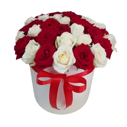 Élégante composition florale en boîte blanche cylindrique ornée d'un ruban rouge satiné, garnie de roses rouges passion et blanches pures harmonieusement arrangées, créée par Fleursdumaroc. Un cadeau raffiné combinant le contraste classique du rouge et blanc, parfait pour exprimer l'amour, l'admiration ou célébrer une occasion spéciale